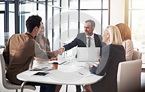 Glad to have you collaborating with us. businesspeople shaking hands during a meeting in an office.