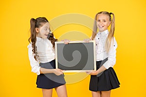 Glad to inform. Schoolgirls informing you. School girls hold blank chalkboard copy space. Girls school uniform hold photo