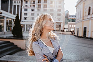Glad white girl with blonde hair enjoying city view. Outdoor photo of pretty caucasian female model standing on the