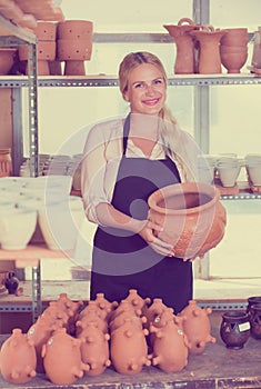 Glad woman potter carrying ceramic vessels