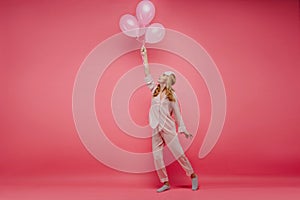 Glad young woman in silk pajama dancing with party balloons. Full-length photo of spectacular birthday girl in night