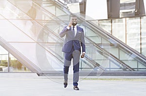 Gladful Black Businessman Talking On Phone Walking In Urban Area