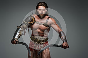 Gladiator with long hair and a beard, donning light armor wearing two swords