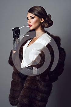 Glam model wearing jewelry and sable coat with sunglasses in her hand