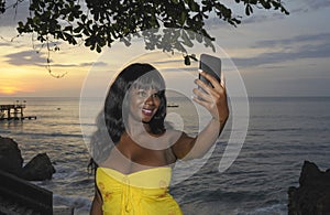 glamorous African American black woman in chic summer dress taking selfie picture or video on mobile phone