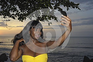 Glamorous African American black woman in chic summer dress taking selfie picture or video on mobile phone