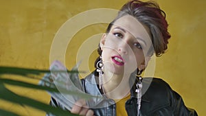 Glamorous aggressive lady in punk rock style party clothes with dark pink hair in black leather jacket and long earrings