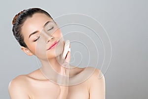 Glamorous beautiful female model applying powder puff for facial makeup concept.