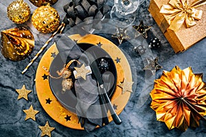 Glamorous black and gold place setting with modern plates for New Years Eve and Christmas