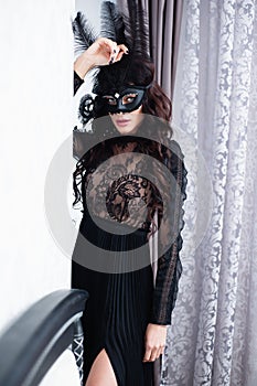 Glamorous brunette lady with a beautiful hairstyle and red lips, in an evening dress, a Venetian black mask with stylish accessori photo