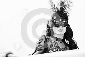 Glamorous brunette lady with a beautiful hairstyle and red lips, in an evening dress, a Venetian black mask with stylish accessori photo