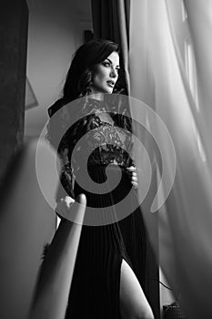 Glamorous brunette lady with a beautiful hairstyle and red lips, in an evening dress, a Venetian black mask with stylish accessori photo