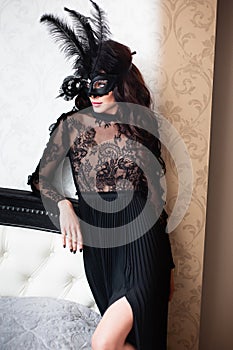 Glamorous brunette lady with a beautiful hairstyle and red lips, in an evening dress, a Venetian black mask with stylish accessori photo