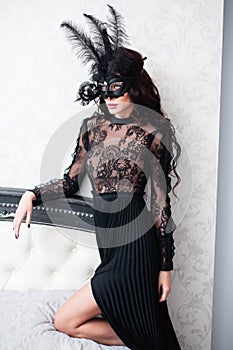 Glamorous brunette lady with a beautiful hairstyle and red lips, in an evening dress, a Venetian black mask with stylish accessori photo