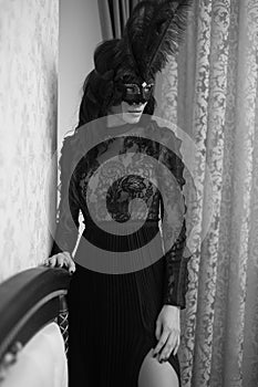 Glamorous brunette lady with a beautiful hairstyle and red lips, in an evening dress, a Venetian black mask with stylish accessori photo