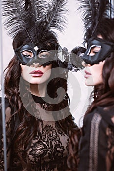 Glamorous brunette lady with a beautiful hairstyle and red lips, in an evening dress, a Venetian black mask with stylish accessori photo