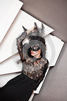 Glamorous brunette lady with a beautiful hairstyle and red lips, in an evening dress, a Venetian black mask with stylish accessori photo