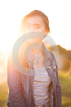 Glamorous brunette woman posing at sunset with sun glare