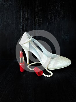 Glamorous composition made of white heels, red lipstick and pearl necklace