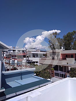 A glamorous distant snapshot of some house buildings from the roof top of a house and some green trees with some clusters of white