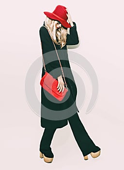 Glamorous fashion blond girl in classic black coat and red hat.