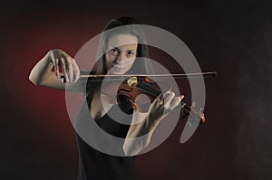 Glamorous girl with a long brown hair playing the violin