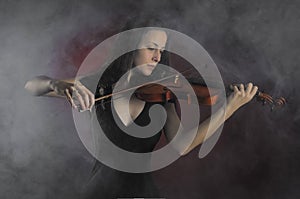 Glamorous girl with a long brown hair playing the violin