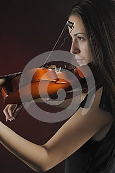 Glamorous girl with a long brown hair playing the violin