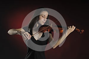 Glamorous girl with a long brown hair playing the violin