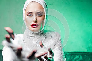 Glamorous mummy. Portrait of a young beautiful woman in bandages Stretching her hand