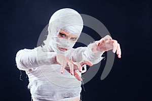 Glamorous mummy woman in bandages all over her body in studio black background. Halloween party or plastic surgery