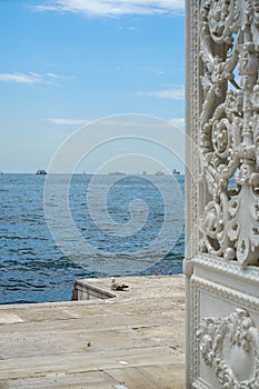 Glamorous ornamental white iron gate open to the Bosphorus strait with sea, ship and blue sky white cloud background, selective