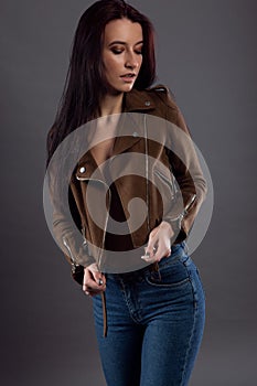 Glamorous portrait of a pretty brunette in jeans and an open jacket on her naked sexy body