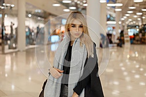 Glamorous pretty stylish young blond woman in a luxurious fashionable vintage vintage coat with a gray fashionable warm scarf