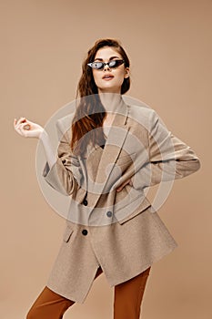 glamorous woman in beige coat and in brown trousers glasses on face makeup model