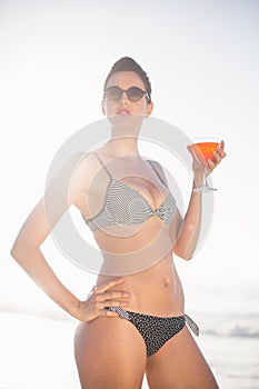 Glamorous woman with a cocktail drink standing on the beach