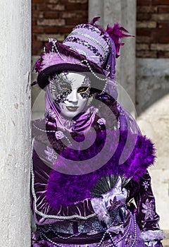 Glamorous woman performer with purple costume and venetian mask during venice carnival