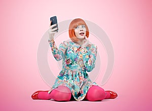 Glamorous young girl sitting with a smart phone on background