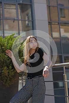 Glamorous young woman wears fashionable dress posing with fluttering hair at grey wall
