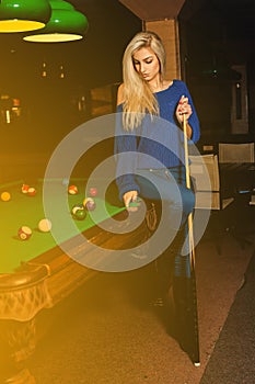 Glamour beauty woman plays billiard on pool table