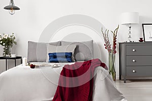 Glamour bedroom interior with a bed dressed in gray linen and cushions with contrasting accents of blue and red. photo