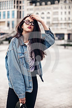 Glamour brunette woman in trendy outfit posing against the urban background,fashion look. Outdoor fashion portrait of stylish