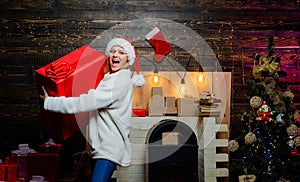 Glamour celebration new year. Blonde Santa woman holding gift box at vintage wall. Portrait of beautiful girl wearing