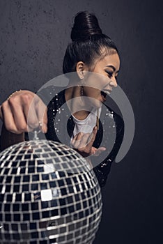 glamour cheerful asian girl with come here gesture holding disco ball