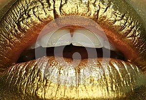 Glamour cosmetic. Gold lips. Gold paint from the mouth. Golden lips on woman mouth with make-up. Sensual and creative