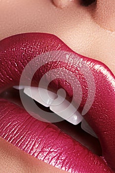 Glamour fashion bright red lips make-up with gold glitter. Macro of woman`s face part. Sexy lip makeup, luxury visage