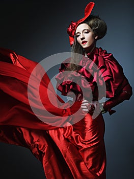 Glamour fashion model in elegance red costume with red hat.