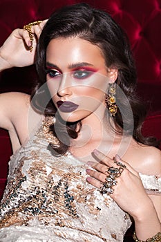 Glamour fashion photo of a beautiful girl with trendy red smokey, blue eyeliner, dark marsala lipstick, curls hairdo