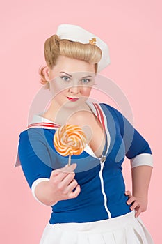 Glamour pin-up lady with big lollipop. Lollipop in hand of retro styled blonde girl. Blond woman in pinup style and candy