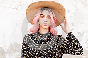 Glamour portrait gorgeous young woman with chic pink hair in stylish beautiful floral dress near wall on street. Lovely girl